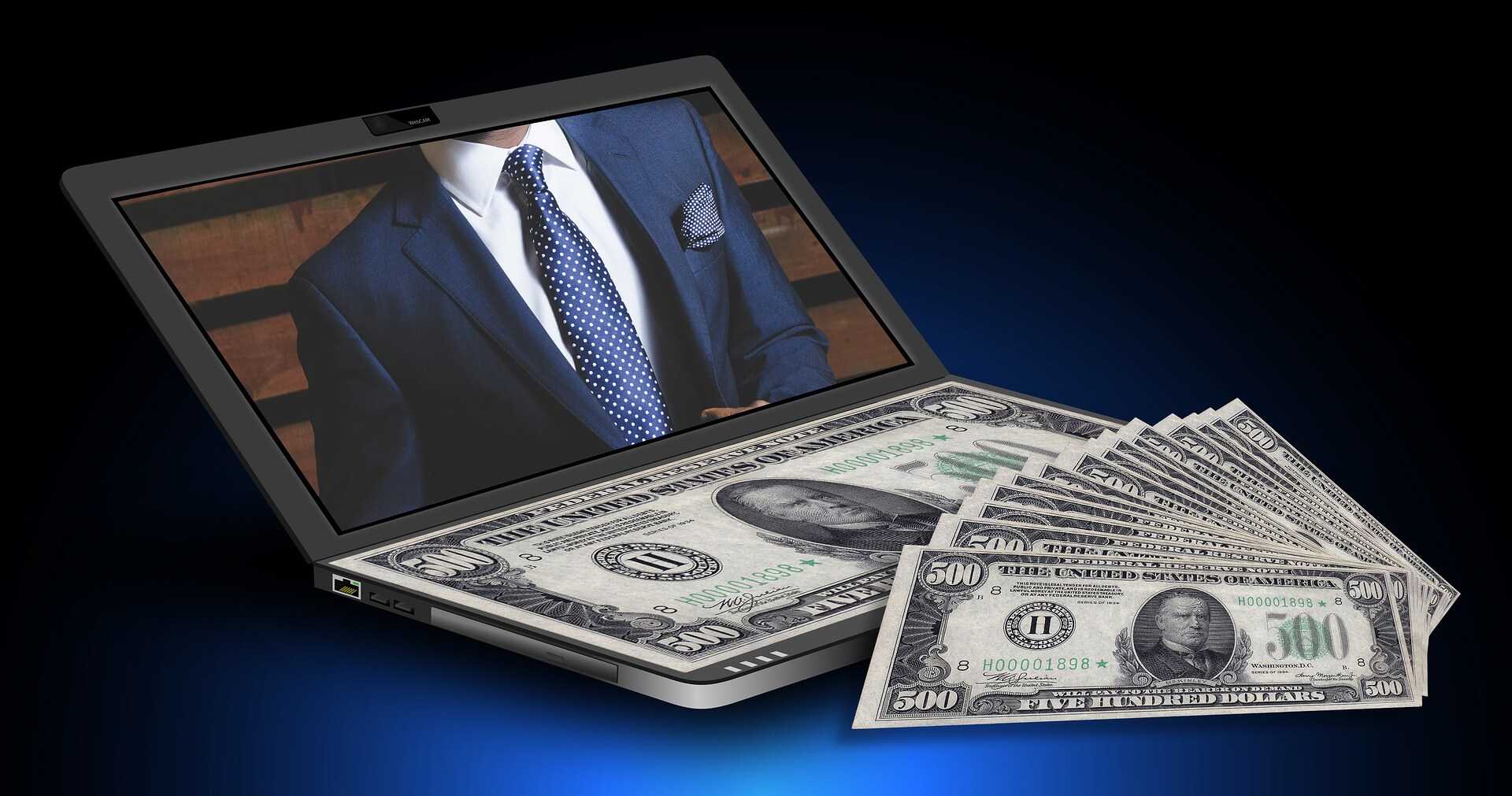 Man in a suit on a laptop screen with $500 on the keyboard