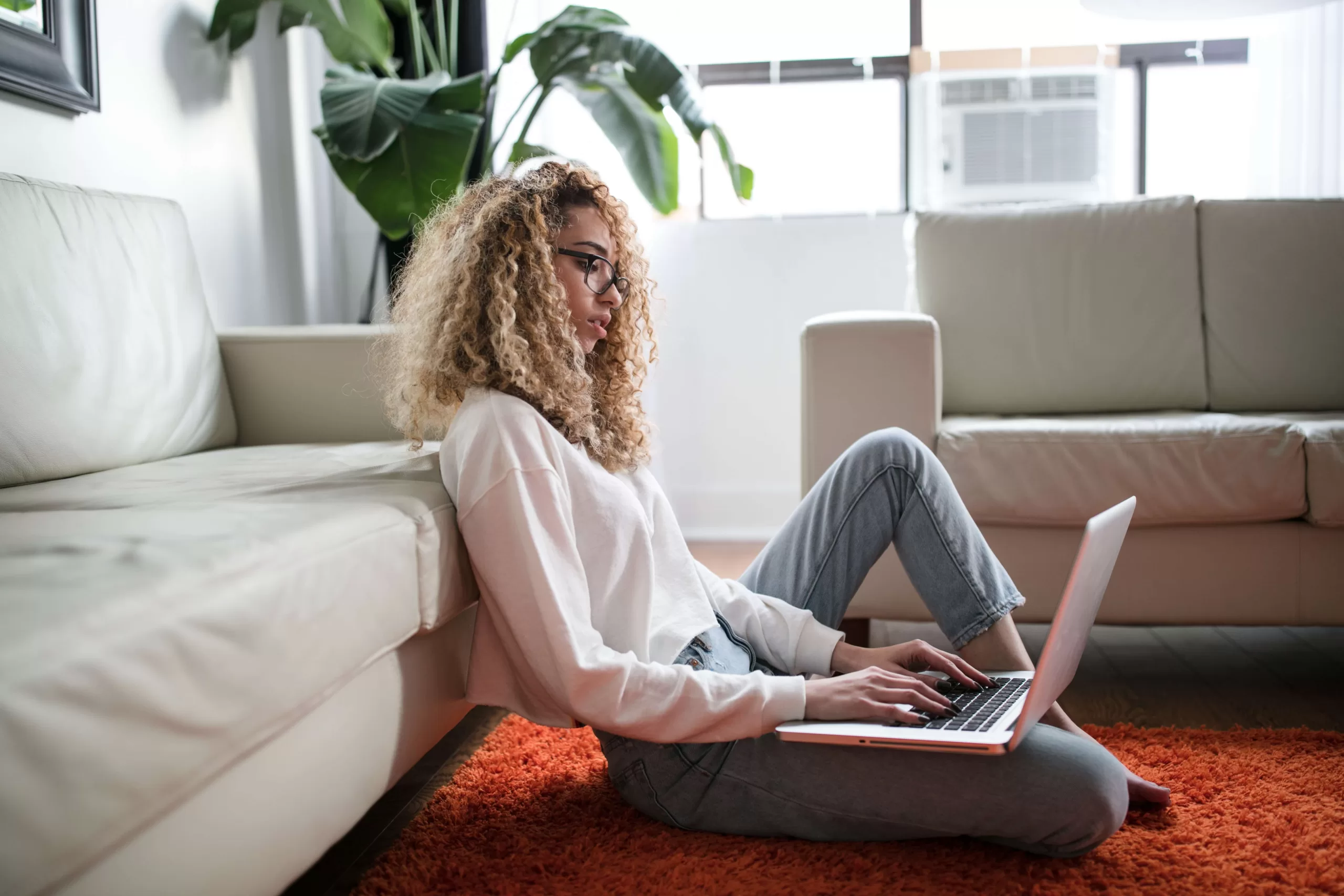 A curly hair woman sitting down searching online on a laptop -cash your opinions