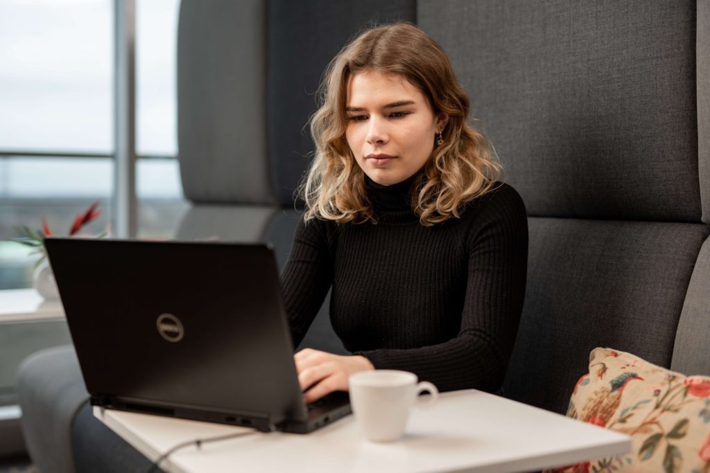 A woman in all black doing survey scams research online