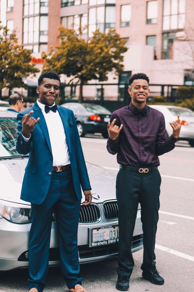 Two passport bros smiling with BMW in background